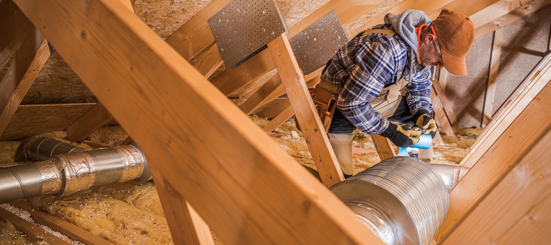 hvac technician installing ductwork in an attic